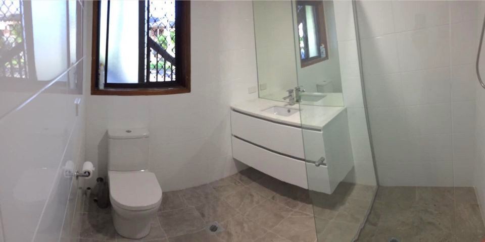 Modern white bathroom renovation with toilet and floating vanity